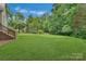 Wide shot of a large, beautifully maintained green lawn with a few shade trees in the backyard at 9040 Scottsboro Dr, Huntersville, NC 28078