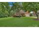 Brick home with lush, mature landscaping, a long driveway, and a two-car garage at 9040 Scottsboro Dr, Huntersville, NC 28078