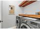 Modern laundry room with gray front load washer and dryer and wood shelf at 921 Northeast Dr, Davidson, NC 28036