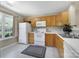 This kitchen features white appliances, wooden cabinetry, and natural light from a window at 10078 Pergola View Ct, Charlotte, NC 28213