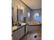 Bathroom featuring double sinks, vanity, and a soaking tub beneath two windows at 111 Crystal Creek Dr, China Grove, NC 28023