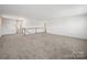 Expansive loft area with plush carpeting, neutral walls and staircase with a wooden banister at 1207 Laggan Ln, Indian Trail, NC 28079