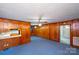 Open living area with wood paneling, blue carpet, and a view into the entryway at 1216 Manchester Ln, Charlotte, NC 28227