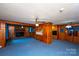 Cozy Gathering room with wood paneling, a brick fireplace, blue carpet, and a ceiling fan at 1216 Manchester Ln, Charlotte, NC 28227