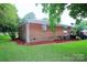 Brick home showcasing a serene backyard with lush landscaping and deck at 1227 Flowe Dr, Matthews, NC 28104
