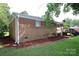 Brick home showcasing a serene backyard with lush landscaping and deck at 1227 Flowe Dr, Matthews, NC 28104
