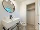 Modern bathroom featuring a round mirror, contemporary sink, and minimalist design with an open closet space at 1227 Flowe Dr, Matthews, NC 28104
