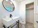 Stylish bathroom showcasing a round mirror, sleek sink, and modern fixtures with an adjacent closet at 1227 Flowe Dr, Matthews, NC 28104