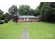 Brick home featuring a well-manicured lawn and inviting walkway to the front door at 1227 Flowe Dr, Matthews, NC 28104