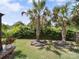 Lush backyard with manicured lawn, trimmed bushes, potted flowers, and stately palm trees at 1252 Winding Path Rd, Lake Wylie, SC 29710