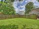 Spacious, fenced backyard featuring lush green grass and mature trees, perfect for outdoor activities and privacy at 1325 Kennon St, Charlotte, NC 28205