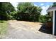 View of a large empty, partially cleared lot showing the side of the blue painted home at 1406 Caldwell St, Gastonia, NC 28052