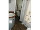 Compact bathroom with a wooden vanity, floral shower curtain, and functional storage options at 166 Eagle Dr, New London, NC 28127
