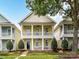 Charming two-story home with double porches, yellow siding, and manicured front yard landscaping at 2003 Trigger Dr, Indian Trail, NC 28079