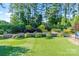 Landscaped backyard with retaining wall, lush greenery, and manicured lawn at 230 Washam Rd, Mooresville, NC 28117