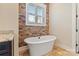 Bright bathroom with freestanding tub, stone accent wall, tile floors, and modern fixtures at 230 Washam Rd, Mooresville, NC 28117