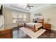 Comfortable bedroom featuring tray ceilings, modern fan, beautiful hardwood floors, and ample natural light at 230 Washam Rd, Mooresville, NC 28117