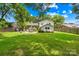Large backyard features a patio with seating, a well-maintained lawn, mature trees, and privacy fencing at 2919 Dunaire Dr, Charlotte, NC 28205