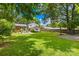 Spacious backyard with green grass, a patio, wooden fence, mature trees, and outdoor recreational space at 2919 Dunaire Dr, Charlotte, NC 28205
