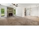 Carpeted living room features a stone fireplace, ceiling fan, and easy access to kitchen and dining area at 4333 Dunwoody Dr, Charlotte, NC 28215