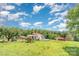 Charming one-story home featuring a red roof, green lawn, and several outbuildings at 439 Neisler Rd, Concord, NC 28025