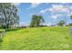 Spacious, grassy yard with partial fencing and mature trees under a beautiful sky at 439 Neisler Rd, Concord, NC 28025