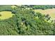 Property with mature trees offering seclusion, complemented by open fields in the distance at 500 Mount Pleasant N Rd, Mount Pleasant, NC 28124