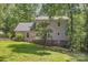 View of the home's rear elevation with a stone foundation and wooden deck nestled among mature trees at 500 Mount Pleasant N Rd, Mount Pleasant, NC 28124