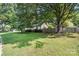 This house showcases a spacious grassy yard with mature trees and a wooden fence at 5229 Milford Rd, Charlotte, NC 28210