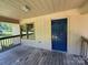 A home's covered front porch with wood flooring, a dark blue door, and an inviting view of the green yard at 5881 Robinhood Rd, Fort Lawn, SC 29714