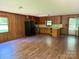Spacious living room with hardwood floors, wood paneled walls, and adjacent kitchen area with modern appliances at 5881 Robinhood Rd, Fort Lawn, SC 29714