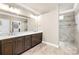 Bathroom with double sink vanity, large mirror, and walk-in shower with decorative tile at 6107 Gold Springs Way, Denver, NC 28037