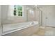 Bright bathroom with a soaking tub under a window with natural light and a glass-enclosed shower at 812 Dogwood Creek Ln, Indian Trail, NC 28079