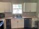 Bright kitchen featuring white cabinets, stainless steel dishwasher, and a stainless steel sink with a view to the yard at 8421 Coulwood Oak Ln, Charlotte, NC 28214