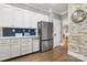 Bright kitchen boasts white cabinets, a stainless steel refrigerator, hardwood floors, and a decorative blue backsplash at 849 Savile Ln, Fort Mill, SC 29715