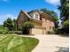 Side view of a brick home showcasing a two-car garage and well-manicured greenery at 9027 Kirkley Ct, Charlotte, NC 28277