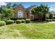 Charming brick home with manicured landscaping, including rounded bushes and a mature tree at 9027 Kirkley Ct, Charlotte, NC 28277