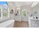 Bright main bathroom with a soaking tub, double vanity, and large windows, showcasing the luxurious amenities at 9027 Kirkley Ct, Charlotte, NC 28277