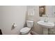 Simple powder room featuring a pedestal sink, toilet, mirror, and towel rack at 9027 Kirkley Ct, Charlotte, NC 28277
