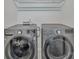 Modern laundry room features gray front loading washer and dryer units with overhead storage at 1115 Macallum Nw Dr, Concord, NC 28027