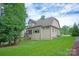 View of back of home from yard, with lush grass and mature trees at 1233 Ladera Dr, Waxhaw, NC 28173