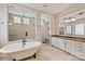 Bright bathroom featuring soaking tub, tiled floors, glass enclosed shower, and dual sinks at 1233 Ladera Dr, Waxhaw, NC 28173