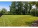 Expansive backyard showcasing green lawn surrounded by mature trees offering privacy and space at 124 Slocumb Ln, Mooresville, NC 28117