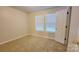 This bedroom includes carpeted floors, a window, and an entrance door at 12450 Stone Garden Dr, Huntersville, NC 28078