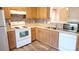 Bright kitchen featuring stainless steel sink, wood cabinets, white appliances, mosaic backsplash, and wood-look floor at 12450 Stone Garden Dr, Huntersville, NC 28078