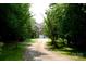 Beautiful home surrounded by mature trees with a long driveway leading to a two-car garage at 13934 Kings Carriage Ln, Charlotte, NC 28278
