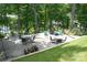 Expansive backyard stone patio with seating and an outdoor fire pit in a wooded setting at 13934 Kings Carriage Ln, Charlotte, NC 28278