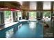 Indoor pool with multiple doors to the outside, lounge chairs, basketball hoops, and an adjacent seating area at 13934 Kings Carriage Ln, Charlotte, NC 28278