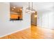 Open-concept with wood floors, this room showcases a modern light fixture and a view into the adjacent kitchen at 14222 Richmond Park Ave, Charlotte, NC 28277
