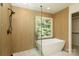 Glass enclosed shower and modern soaking tub beneath a window at 21514 Gulfstar Ct, Cornelius, NC 28031